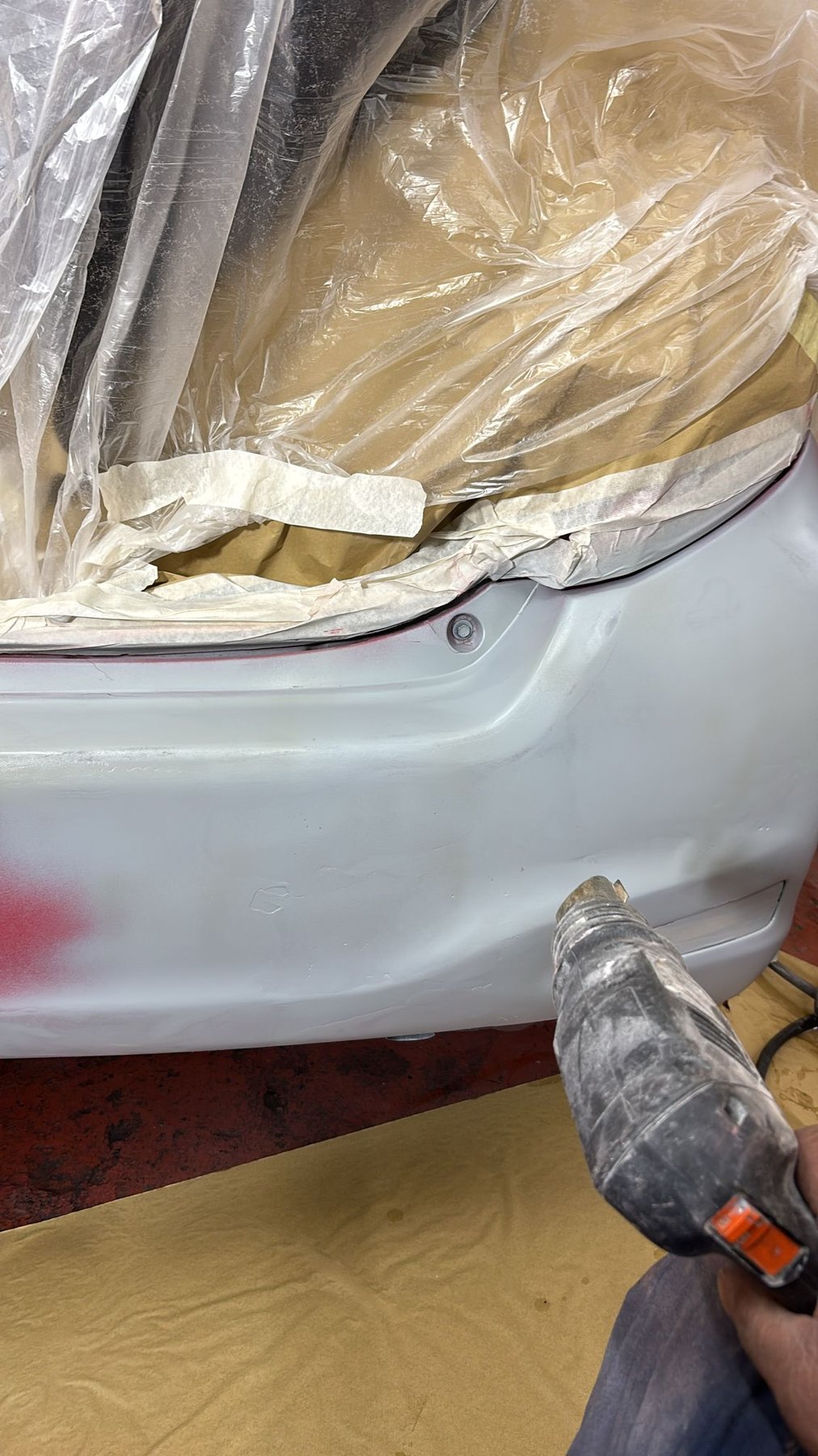 A car bumper masked with brown paper and sanded ready for paint