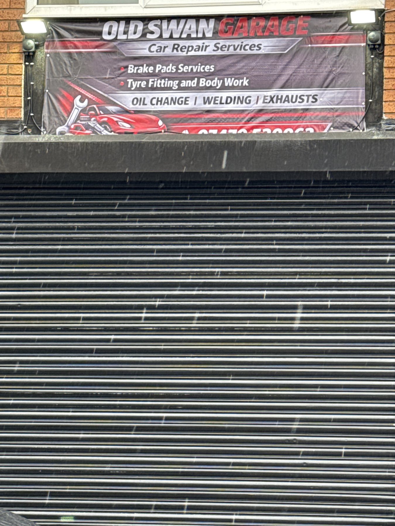 The Old Swan Garage banner above the garage shutter in daylight